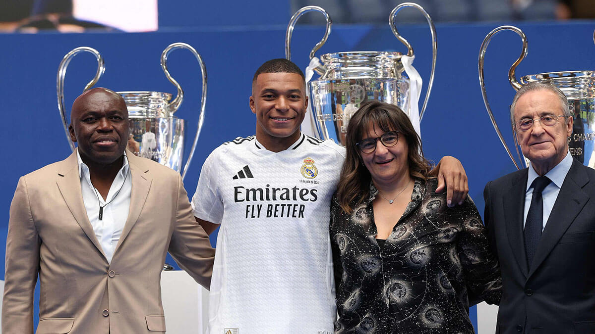 pEl delantero francés Kylian Mbappé (2.a izq.) posa con sus padres Wilfrid Mbappé (izq.) y Fayza Lamari (2.a der.) y el presidente del Real Madrid, Florentino Pérez, durante su primera aparición como jugador del Real Madrid en el Estadio Santiago Bernabéu de Madrid el 16 de julio de 2024 - AFP/PIERRE-PHILIPPE MARCOU /p 